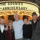 Richard Donner (center) stands in front of a theater marquee at The Goonies’ 25th anniversary celebration with (from left): Joe Pantoliano, Jeff Cohen, Lupe Ontiveros, Ke Huy Quan, Robert Davi, and Corey Feldman.